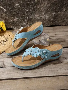 Detailed view of light blue wedge flip-flop sandals with flower decorations