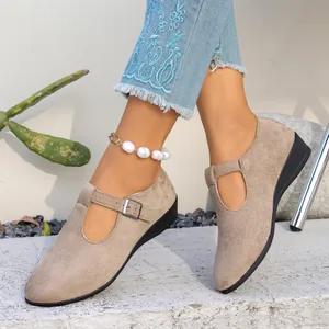 Gros plan sur des chaussures compensées en daim beige avec boucle et découpe