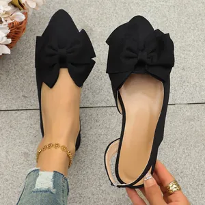 Close-up of elegant black pointed-toe flat sandals with large bow and slingback strap