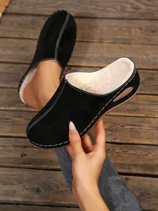 Close-up of black closed-toe clogs with white stitching and faux shearling lining