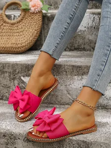Close-up of elegant pink bow flat sandals with rhinestone edge for summer beach wear.