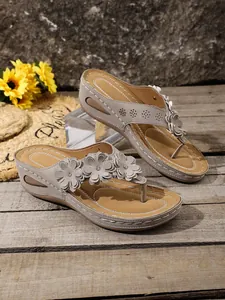 Close-up of women's wedge thong sandals with 3D flower accents and stitching