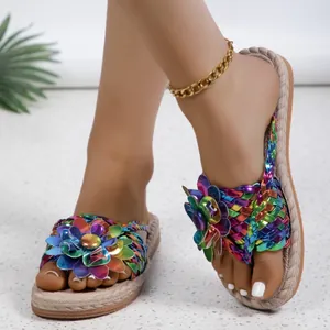 Detailweergave van regenboog metallic gevlochten strandsandalen met een grote bloem.