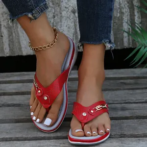Tongs à talons compensés rouges avec boucle en métal et strass sur une terrasse en bois