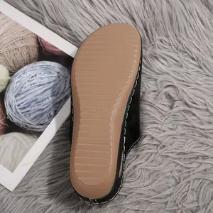 Detailed close-up view of the non-slip tan ridged sole on women's black wedge mules slippers.