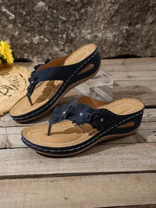Detailed view of navy blue wedge flip-flops with decorative flowers on the straps