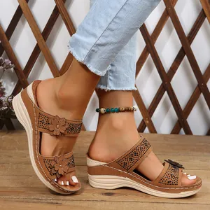 Detail view of brown wedge sandals featuring 3D floral accents and rhinestone embellishments.