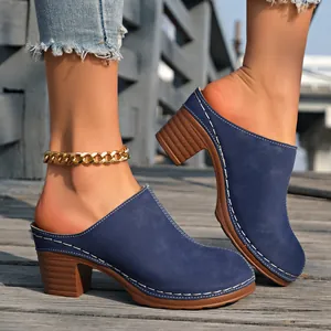 Mules bleu marine à bout fermé et talon épais avec surpiqûres sur un pont en bois