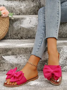 Close-up of stylish pink flat bow sandals with rhinestone edge for summer beach wear