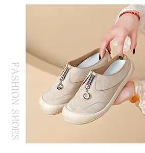 Close-up detail of beige suede loafers featuring front zipper closure and comfortable platform sole