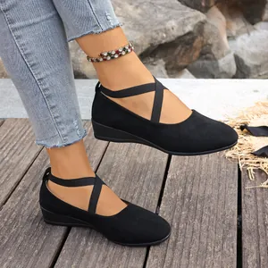 Gros plan de chaussures compensées en daim noir avec des brides croisées au pied