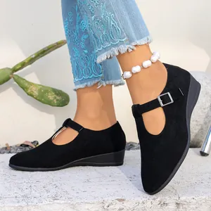Gros plan de chaussures compensées en daim noir à bout pointu avec bride à boucle