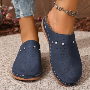 Detailed macro view of navy blue closed-toe mules with perforated design and metal studs