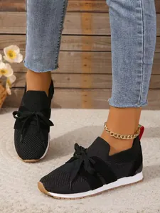 Detailansicht der schwarzen atmungsaktiven Fly-Knit Slipper mit dekorativer Schleife