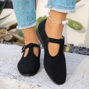 Gros plan de chaussures compensées noires en daim à bride en T pour femmes en extérieur