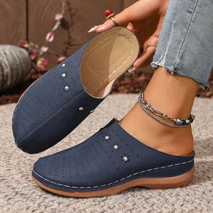 Close-up of blue perforated wedge mules showing the cushioned interior and outer studs.