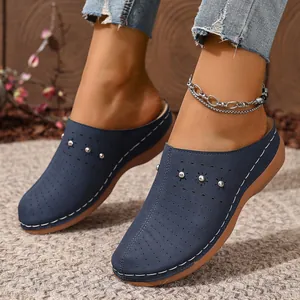 Close-up of navy blue platform clogs with decorative studs and laser-cut patterns