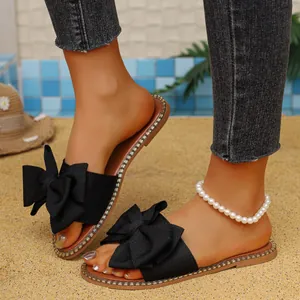 Elegant black flat sandals with large bow and rhinestone trim for summer beach wear