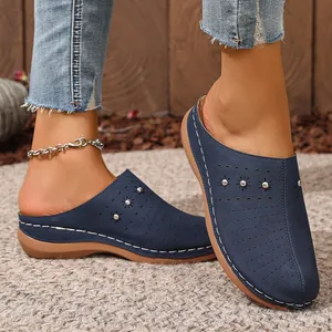 Detail view of stylish blue wedge clogs with decorative stitching and laser-cut patterns.