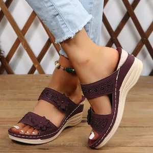Detailed view of purple women's wedge sandals with floral appliques and black studs