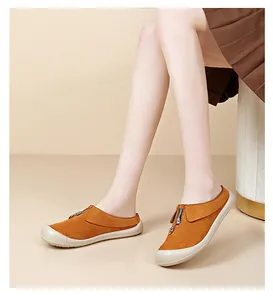 Detailed shot of model wearing orange suede platform mules with front zipper design