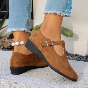 Gros plan de chaussures compensées en daim marron pour femme avec bout pointu et boucle.