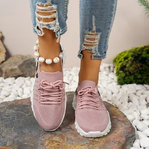 Gros plan de baskets en maille rose respirante portées avec un jean déchiré