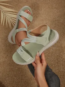 Close-up detail of light green wedge sandals with adjustable velcro straps and stitching
