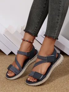 Detailed view of navy blue wedge sandals featuring cross-straps and adjustable velcro closure