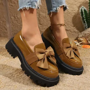 Detailansicht brauner Lackleder-Loafer mit großer Schleife und dicker Profilsohle.