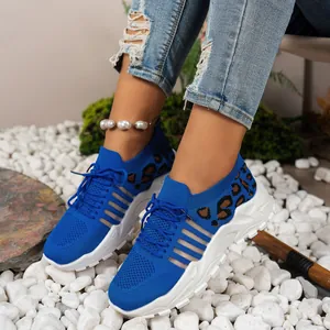 Gros plan de baskets en maille bleue à imprimé léopard sur des pierres blanches.