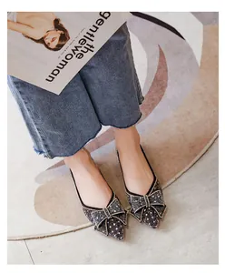 Top view detail of elegant black glitter pointed-toe flats with decorative bow accents