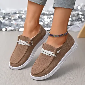 Close-up of brown canvas loafers featuring white decorative laces and thick textured white soles