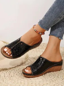 Stylish black crocodile print wedge sandals for women with peep-toe design worn on feet