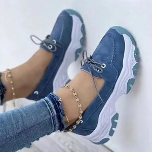 Close-up of blue lace-up sneakers with thick platform soles worn with denim jeans