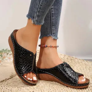 Close-up of black crocodile-patterned wedge sandals with sparkling details