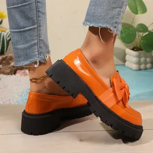 Vibrant orange patent leather loafers featuring a stylish bow and platform sole