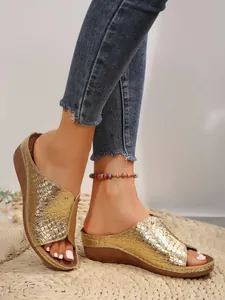 Close-up detail showing the textured gold finish and wedge sole of these summer slides