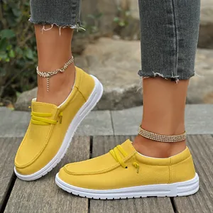 Close-up of women's yellow canvas loafers with white sole worn outdoors by a model