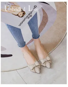 Detail view of French pointed flat shoes with elegant bow and sparkly rhinestones.