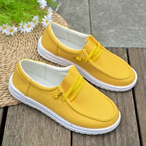 Close-up of vibrant yellow canvas loafers with white soles and decorative laces