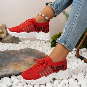 Gros plan sur des baskets en maille rouge avec imprimé léopard et semelles blanches