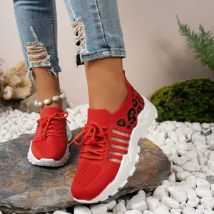 Détail de baskets en mesh rouge à imprimé léopard portées avec un jean en denim usé