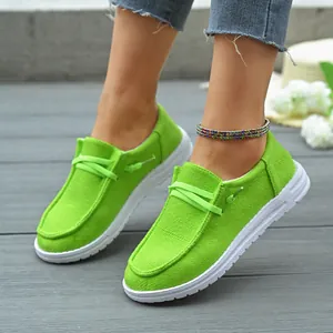 Detailed close-up of vibrant lime green canvas loafers with white soles on grey deck