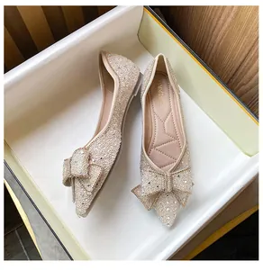 Detail of elegant champagne pointed-toe flats with sparkling rhinestone bow decoration.