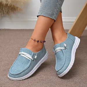 Close-up shot of women's casual light blue canvas loafers featuring white laces and slip-on style