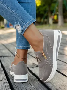 Nahaufnahme grauer Wildleder-Plateau-Sneaker mit Reißverschluss und goldenem Emblem