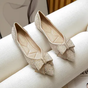 Elegant champagne-colored pointed-toe flats with glitter finish and chic bow detail