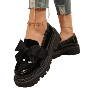 Elegant black patent leather loafers for women featuring a large bow and chunky sole