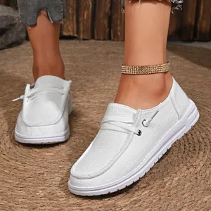 Detail shot of white casual canvas loafers for women with stylish gold anklet detail.